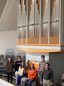 7 students smiling with an organ.